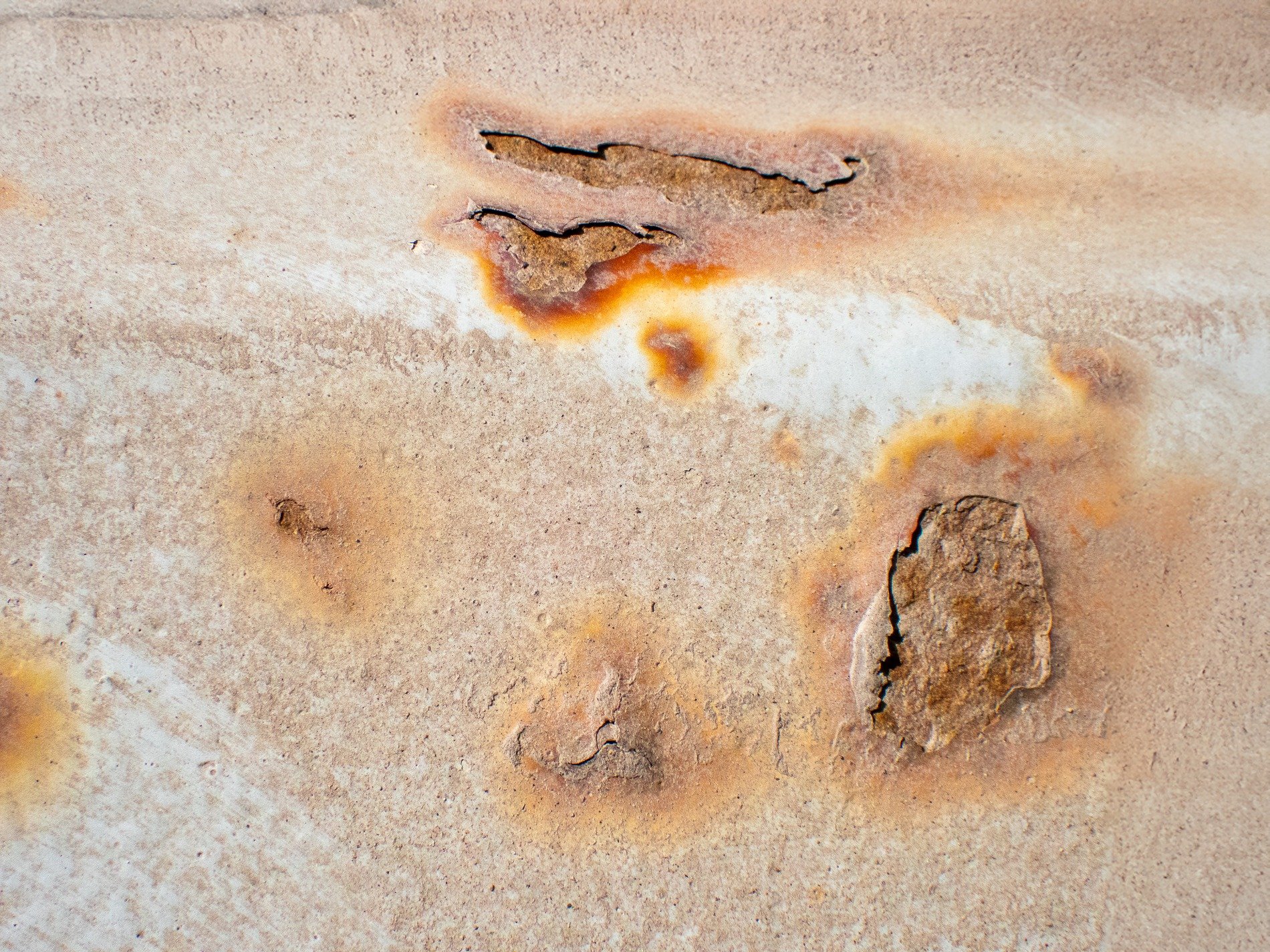 White paint peels away, orange rust blooms from beneath, metal turns to dust