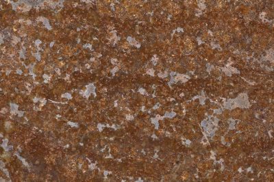 Iron turns to dust, orange blooms on grey surface, time consumes the steel