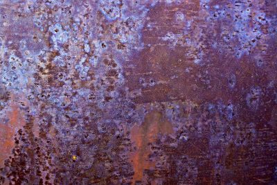 Purple iron blooms, rust devours the heavy plate, colors bleed through time