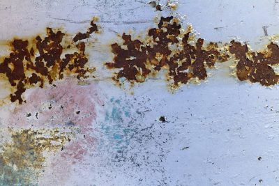 Cold blue steel decays, orange rust eats through the paint, time flakes off the skin