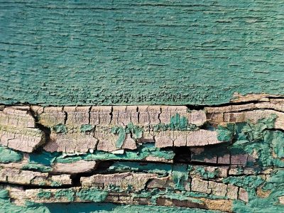Green paint flakes away, dry wood splits in deep channels, time strips the color