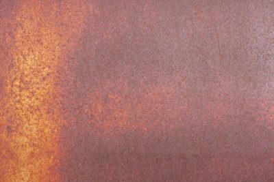 Iron skin decays, orange dust blooms on the steel, time eats through the sheet