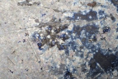 Cobalt stains the steel, dark scars bloom across the cold, metal tells the tale