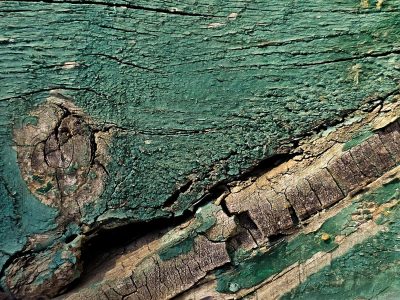 Blue layers peel back, white flakes meet the grey, grit holds the surface