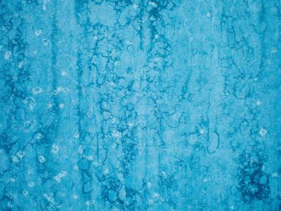 Blue mist holds the field, vertical streaks trace the skin, light catches the grit