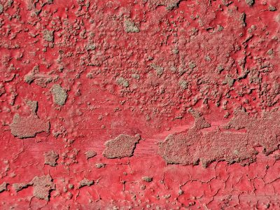 Red paint peels away, bubbles rise from rusted depths, cracked skin reveals age