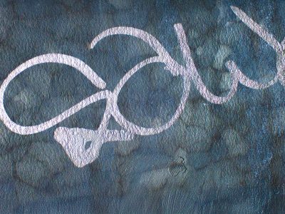 Blue paint on the window, jagged flakes meet the clear glass, light catches the grit