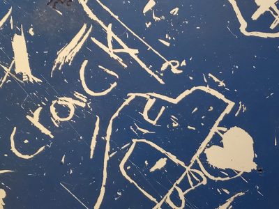 Blue skin holds the white, scratched lines mark the metal plate, grit meets the shadow