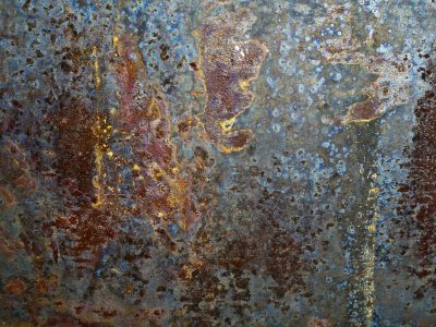 Blue skin peels away, brown rust islands on the steel, time marks the surface