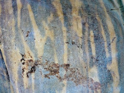 Grey waves meet the sand, stripes of time across the rock, silent patterns wait