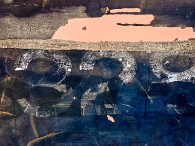 Cracked white ink remains, salmon patches on dark blue, metal tells a tale.