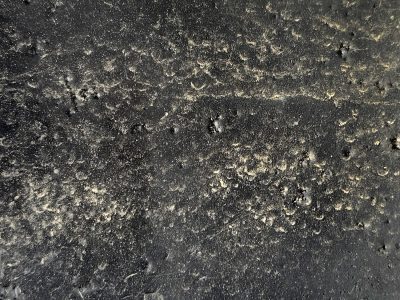 Dark paint pits and bumps, black skin holds the sandy grit, night meets heavy dust