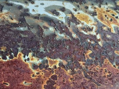 Deep rust eats the blue, jagged edges on the steel, decay takes the light