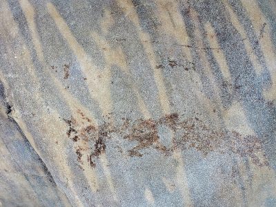 Grey bands in the stone, mineral veins trace the grain, time carves out the rock