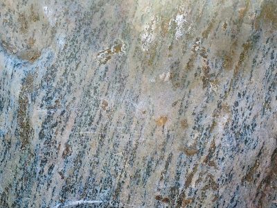 Grey grains flow in lines, vertical veins trace the skin, mineral stays deep