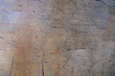 Grey skin has deep pits, jagged scars mark up the field, light catches the grit