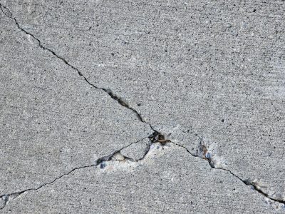 Grey stone splits apart, diagonal crack cuts deep, grit falls in the void