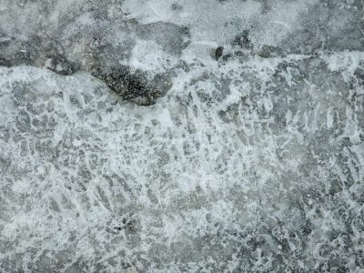 Frozen bubbles rise, grey stone sleeps beneath the ice, winter's hard embrace