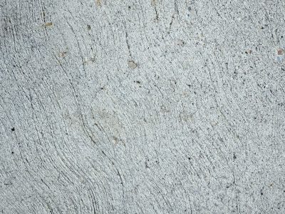 Rough gray surface set, sweeping lines cross cold cement, grit and stone remain