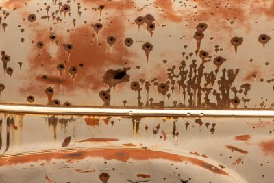 Iron skin is torn, orange rust weeps from the holes, silence holds the steel