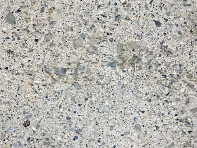 Grey stones in the mix, rough concrete holds the pebbles, grit fills the surface
