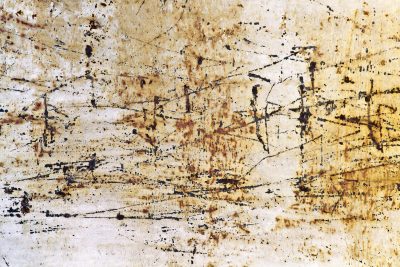 Heavy rust scales on car steel, orange and brown minerals claim the body, grit holds the decay