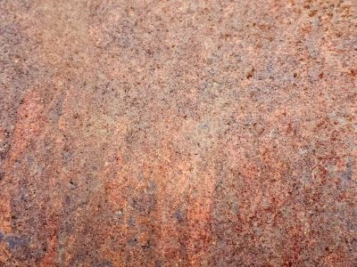 Heavy rust scales, orange and brown minerals claim the steel, grit holds the decay