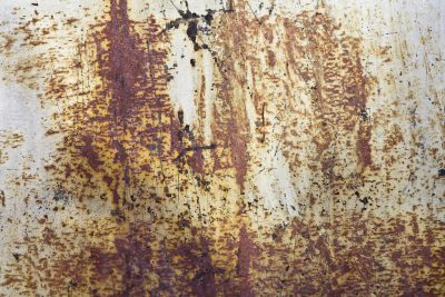 Orange dust on steel, rough pits scar the heavy plate, rust claims the finish