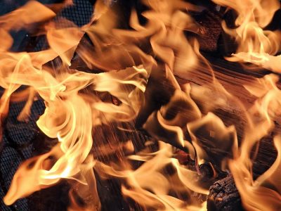 Orange flames flicker, glowing heat on the dark wood, fire claims the harvest