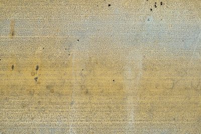 Yellowed paint decays, tiny black pits dot the plane, metal starts to show