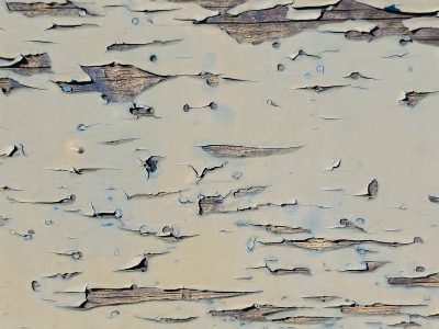 Pale blue paint peels back, dry wood waits beneath the cracks, grit holds the old lines