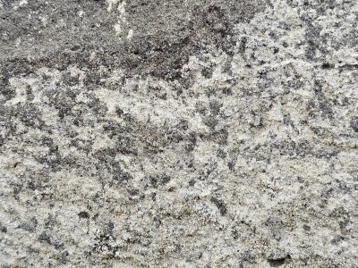 Gray rock holds its ground, salt and pepper grains align, worn by passing years