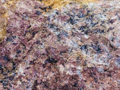 Pink crystals cluster, dark minerals dot the face, earth's hard heart revealed