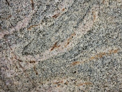 Grains of speckled grey, orange veins map out the past, solid ancient stone