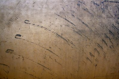 Steel etched by the years, dark marks scar the silent grey, weathered surface waits