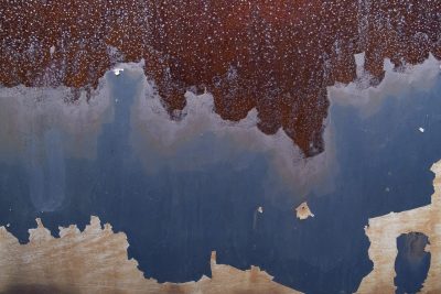 Rusty peaks descend, blue paint meets a jagged edge, layers wear away