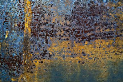 Purple rust holds fast, dark minerals bloom on the steel, time claims the plate