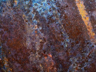Purple rust holds fast, red minerals bloom on dark, time wears down the plate