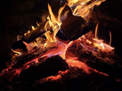 Red heat on the log, orange flames lick the dark wood, ash turns into smoke