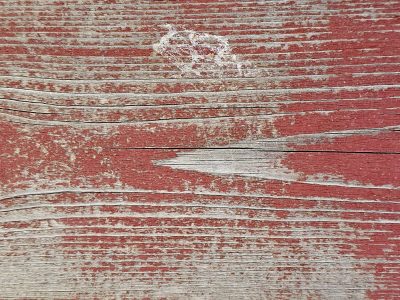 Red paint on the wood, weathered grain shows through the cracks, old years leave a mark