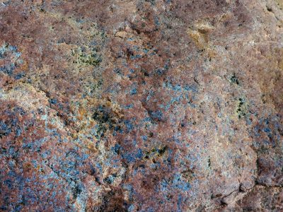 Red rock holds the blue, mineral veins trace the dark, pits scar the finish
