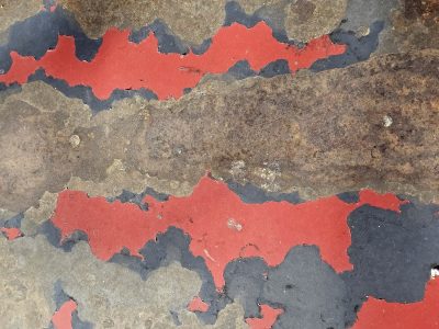 Red skin peels away, brown rust eats the heavy steel, flakes drift in the air