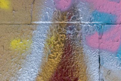 Red skin peels back, yellow layers show beneath, grit holds the old mark