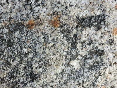 Rough aggregate in the mix, grey concrete holds the stones, time wears the pavement