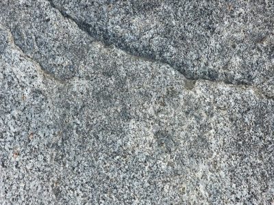 Rough granite surface, grey stone meets a jagged ridge, ancient frozen dust