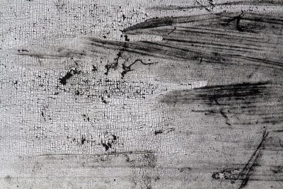 Rough pits scar the grey, jagged lines trace the surface, time wears the finish