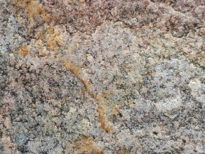 Rough stone greets the day, rusty veins cut through the grain, time carves out the depth