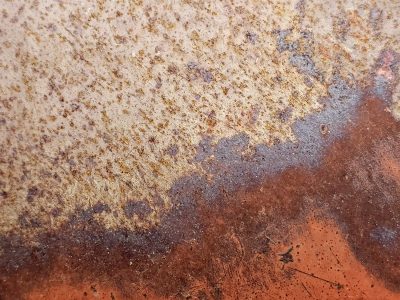 Rust blooms on the plate, orange dust meets the pale grain, metal turns to earth