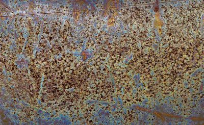 Silver metal pitted, grey circles mark the heavy plate, grit holds the finish