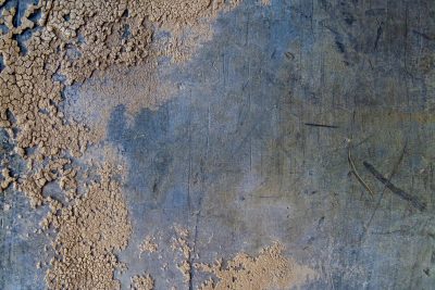 Dry earth meets the blue, scratches mar the metal skin, layers peel away
